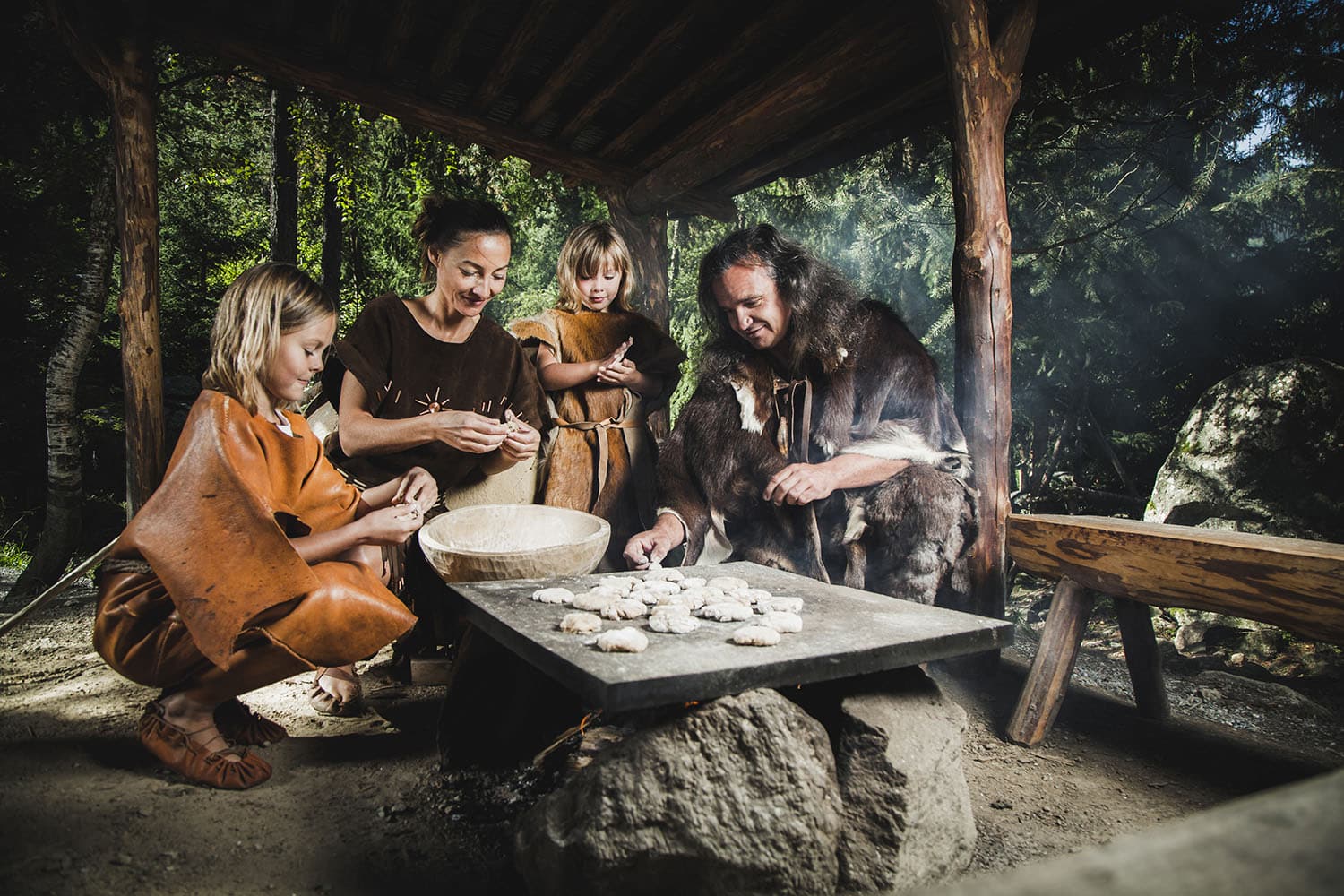 Steinzeitliche Familie beim Brotbacken im Ötzi-Dorf